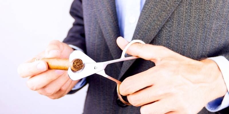 guy in suit holding a cigar and cigar scissors