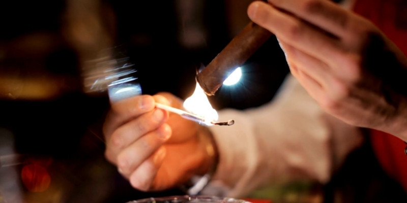 toasting the foot of a cigar with a match